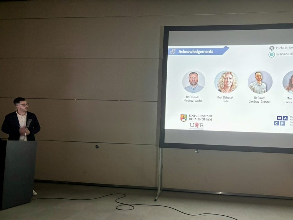 Michail Arvanitidis presenting beside a projected acknowledgements slide